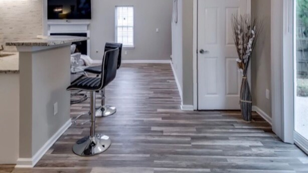A modern kitchen with a flat-screen TV, a dining area with two chairs, and a hallway with a patterned floor. - *Modern oasis 7 mins from Atlanta airport (College Park)