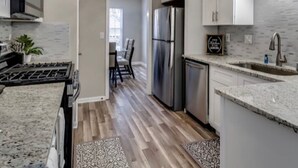 A modern kitchen with stainless steel appliances, a granite countertop, and a patterned rug. - *Modern oasis 7 mins from Atlanta airport (College Park)
