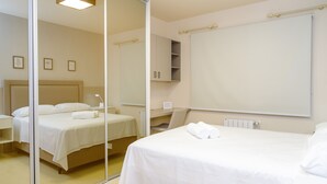 Une chambre d’hôtel avec deux lits, un grand miroir, une armoire et un radiateur.
