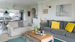 A living room with a grey sofa, a wooden coffee table, and a dining area with a table and chairs.