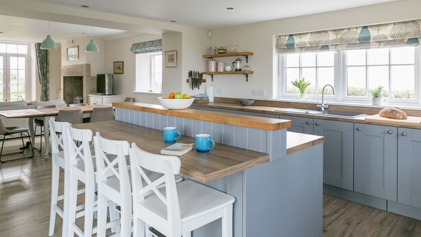 A modern kitchen with a central island, grey cabinets, and a window with a view.