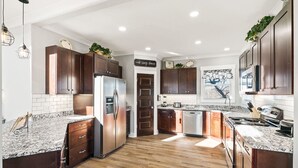 Une cuisine moderne avec des meubles en bois foncé, des plans de travail en granit et des appareils électroménagers en acier inoxydable.