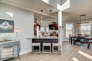 A spacious kitchen with a central island, pendant lighting, and a dining area with a bench.