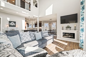 A spacious living area with a large sectional sofa, a fireplace, and a flat-screen TV mounted above it.