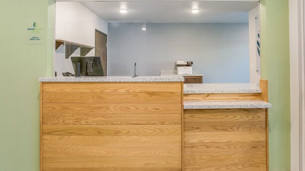 A wooden cabinet with a granite countertop in a room with light green walls.