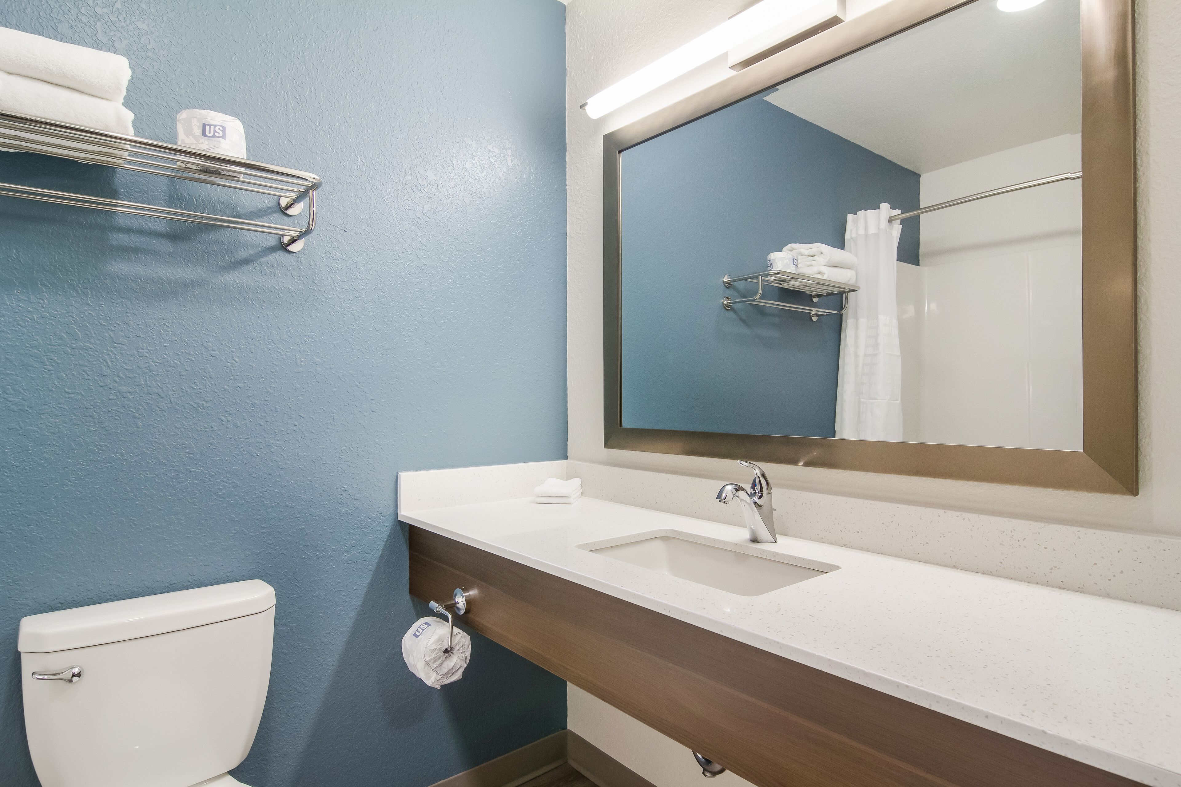 A bathroom with a white sink, a mirror, a towel rack, and a toilet.