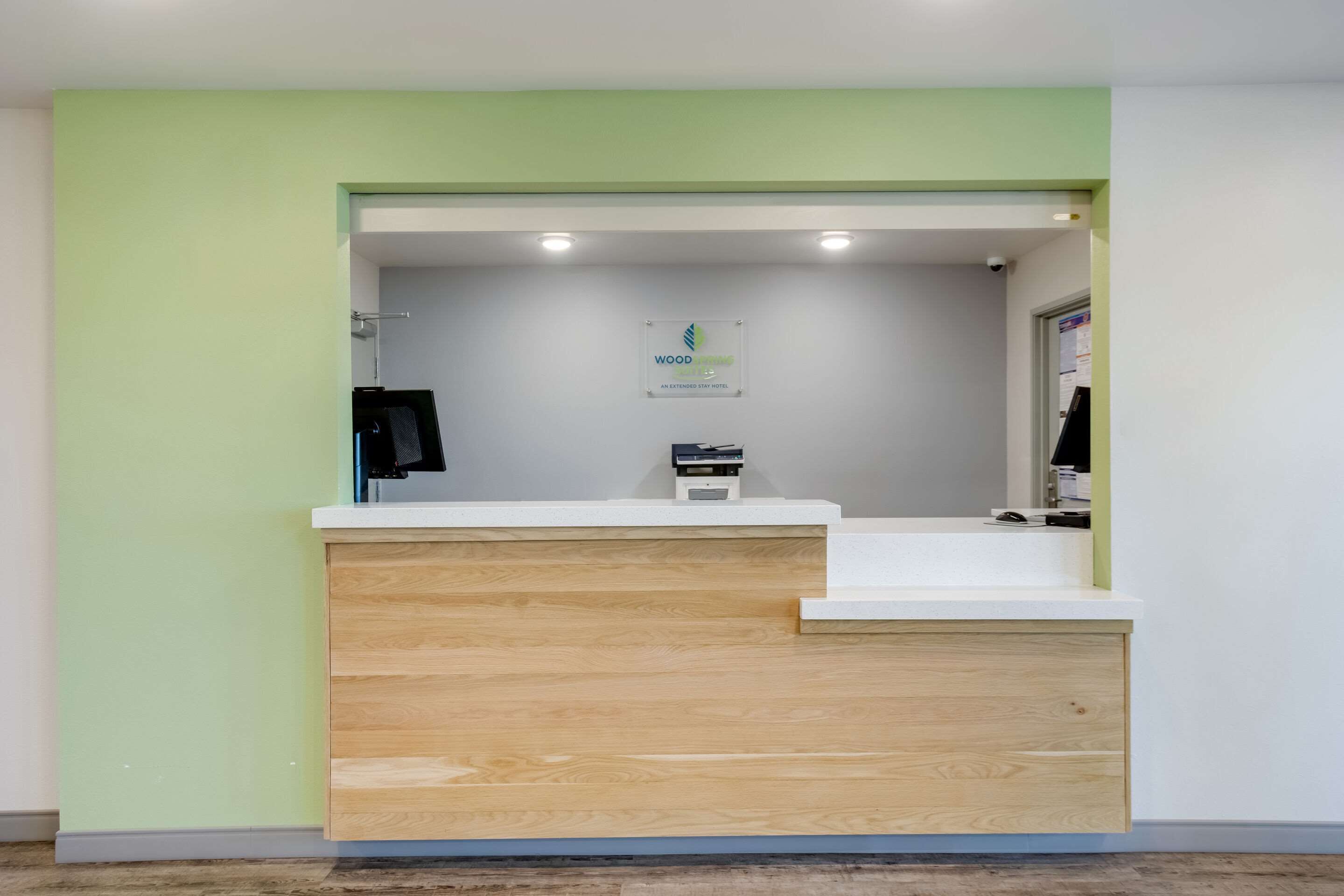 A reception area with a wooden counter, a sign for Wood Hotel, and a coat rack.