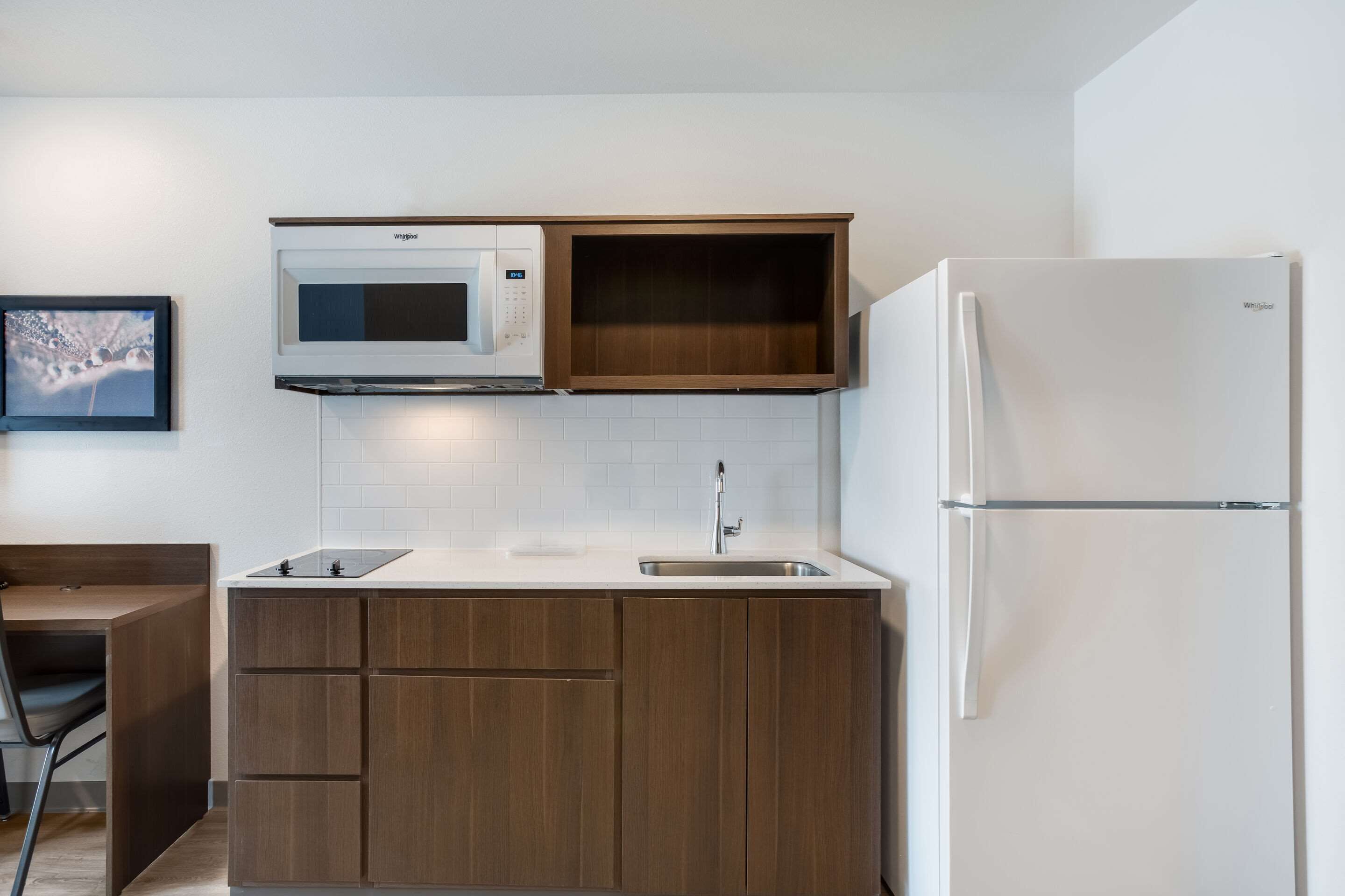 Una cocina compacta con microondas, lavamanos y refrigerador.