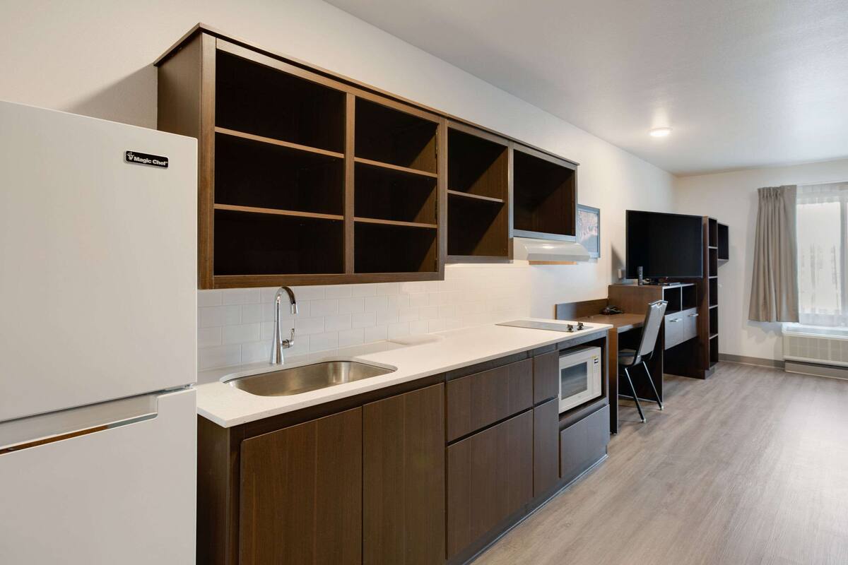 Een moderne keuken met een ingebouwde magnetron, een spoelbak en een eethoek met een stoel en tafel.
