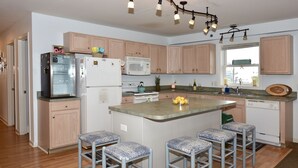 A modern kitchen with wooden cabinets, stainless steel appliances, and a central island with bar stools.