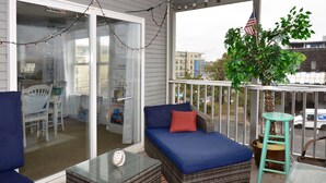 A balcony with wicker furniture, a glass door, and an American flag.