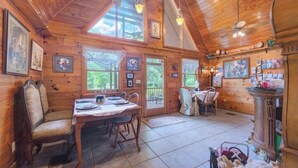 A wooden cabin interior with a dining area, a fireplace, and a large window. - Cabin On The Lake (Lake Helen)