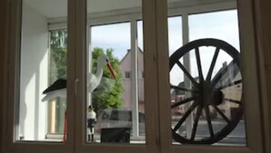 Een raam met een groot wiel en een beeldhouwwerk van een witte vogel.