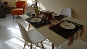 Een eethoek met een tafel gedekt voor twee personen, inclusief een fles wijn, een taart en borden.