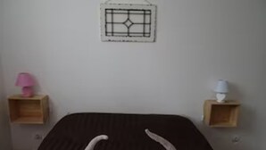 Een slaapkamer met een bed, twee nachtkastjes en een decoratie aan de muur.