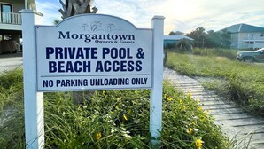Schild für einen privaten Pool- und Strandbereich, das Parken untersagt und nur das Ausladen erlaubt.