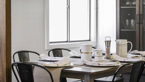 A dining table set with white plates, napkins, and a pitcher, with chairs around it. - Happy Haven (Thornton)
