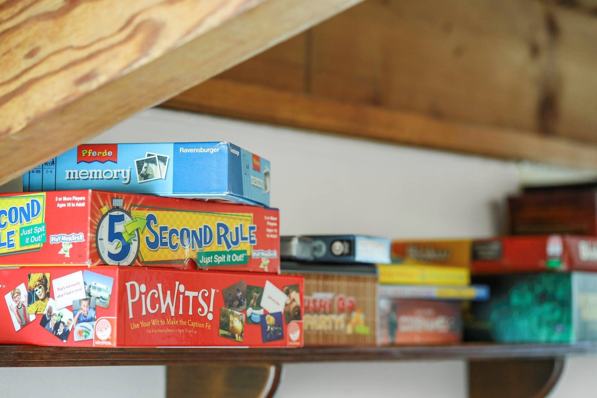 A shelf with various board games, including 'Pferde memory', 'Ravensburger', 'SECOND RULE', and 'Picwits!'.