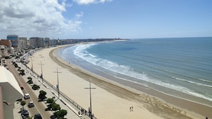 Eine Küstenstadtlandschaft mit breitem Strand, einer Uferpromenade und Hochhäusern im Hintergrund.
