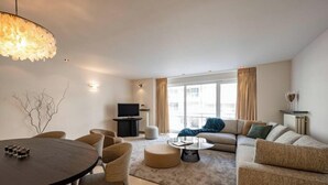 Een moderne woonkamer met een ronde eettafel, banken, een salontafel en een televisie.