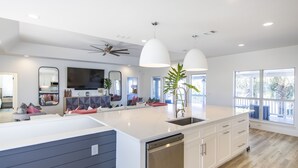 Una cocina moderna con una isla grande, armarios blancos y un lavavajillas integrado.