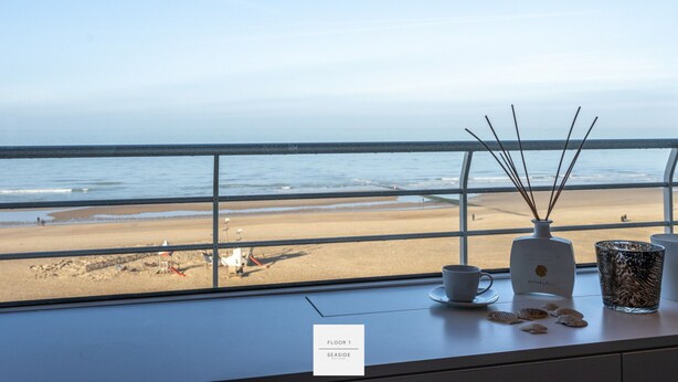 A window view of a beach with a sign indicating 'Floor 1, Seaside'. - Marble Floor, full comfort sea view, parking incl. (Oostende)
