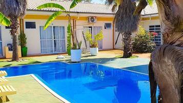 Una piscina al aire libre, sombrillas, sillones reclinables de piscina