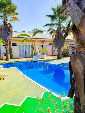 Una piscina al aire libre, sombrillas, tumbonas