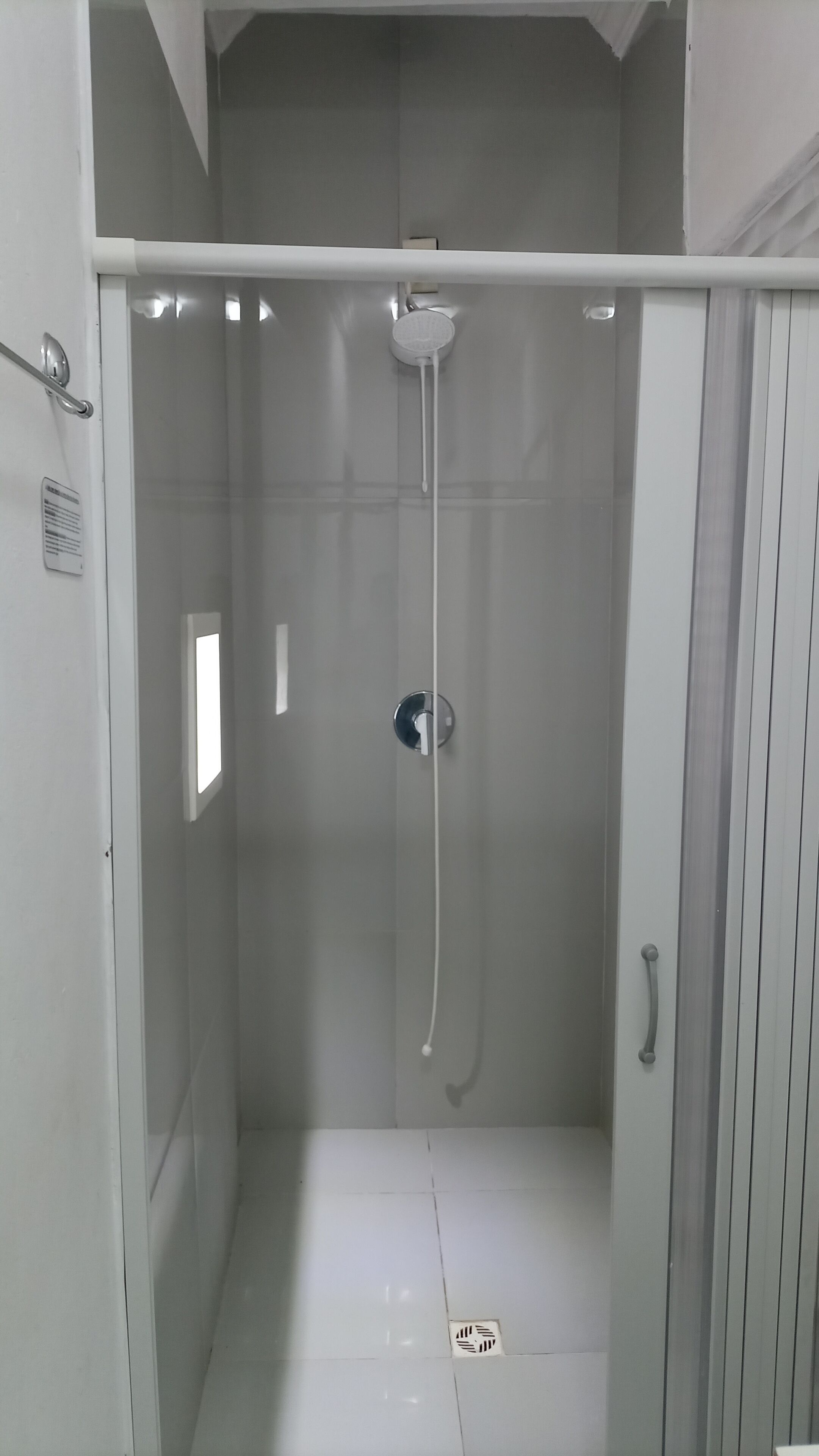 A small, enclosed shower area with a handheld showerhead and a wall-mounted faucet.