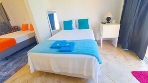 Een hotelkamer met een bed, een nachtkastje met een lamp en een raam met gordijnen.