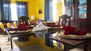 Una mesa de comedor dispuesta con servilletas rojas, aros de servilleta blancos y un centro de mesa de cristal.
