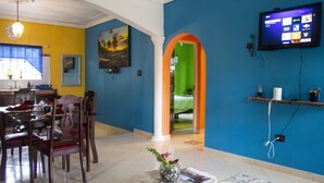 Un comedor con una mesa y sillas, un cuadro en la pared y un televisor montado.