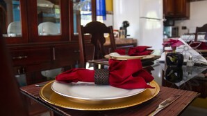 A dining table set with a white plate, red napkin, and gold rimmed plate. - El Castilito (Brown's Town)
