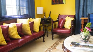 Una sala de estar con un sofá rojo y un sillón, una mesa de centro y un florero con flores.