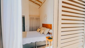 Une chambre à coucher avec un lit, une table de chevet et une fenêtre avec des stores.