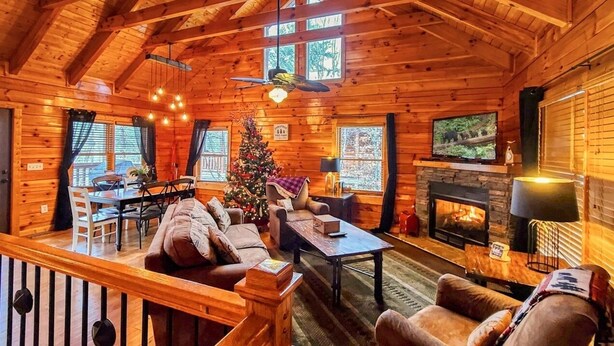 A cozy log cabin interior with a fireplace, a television, and a Christmas tree. - Ridge resort getaway cabin, 2 Bds, 3 Ba, Pigeon Forge, Smoky Mountains (Pigeon Forge)