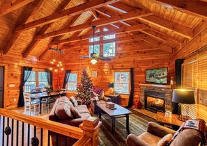 A cozy log cabin interior with a fireplace, a television, and a Christmas tree. - Ridge resort getaway cabin, 2 Bds, 3 Ba, Pigeon Forge, Smoky Mountains (Pigeon Forge)