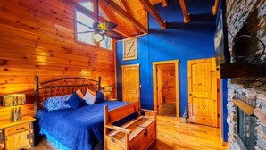 A wooden cabin bedroom with a bed, dresser, and a stone wall. - Ridge resort getaway cabin, 2 Bds, 3 Ba, Pigeon Forge, Smoky Mountains (Pigeon Forge)