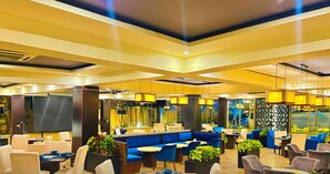 Un moderno vestíbulo de hotel con zonas de estar, un mostrador de recepción y amplios ventanales.