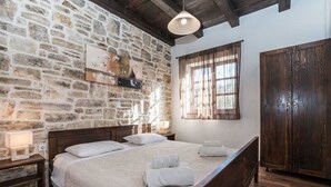 A bedroom with a stone wall, wooden bed, and a wardrobe.