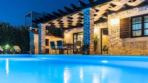 A swimming pool with a pergola and stone walls.