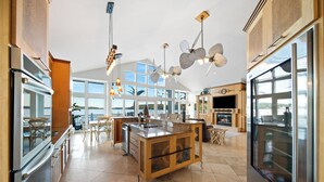 A spacious kitchen with a large island, modern appliances, and large windows offering views. - Brownstone - Amazing 3,600 SF home SLEEPS 18 --Game room--HOT TUB (Sunrise Beach)