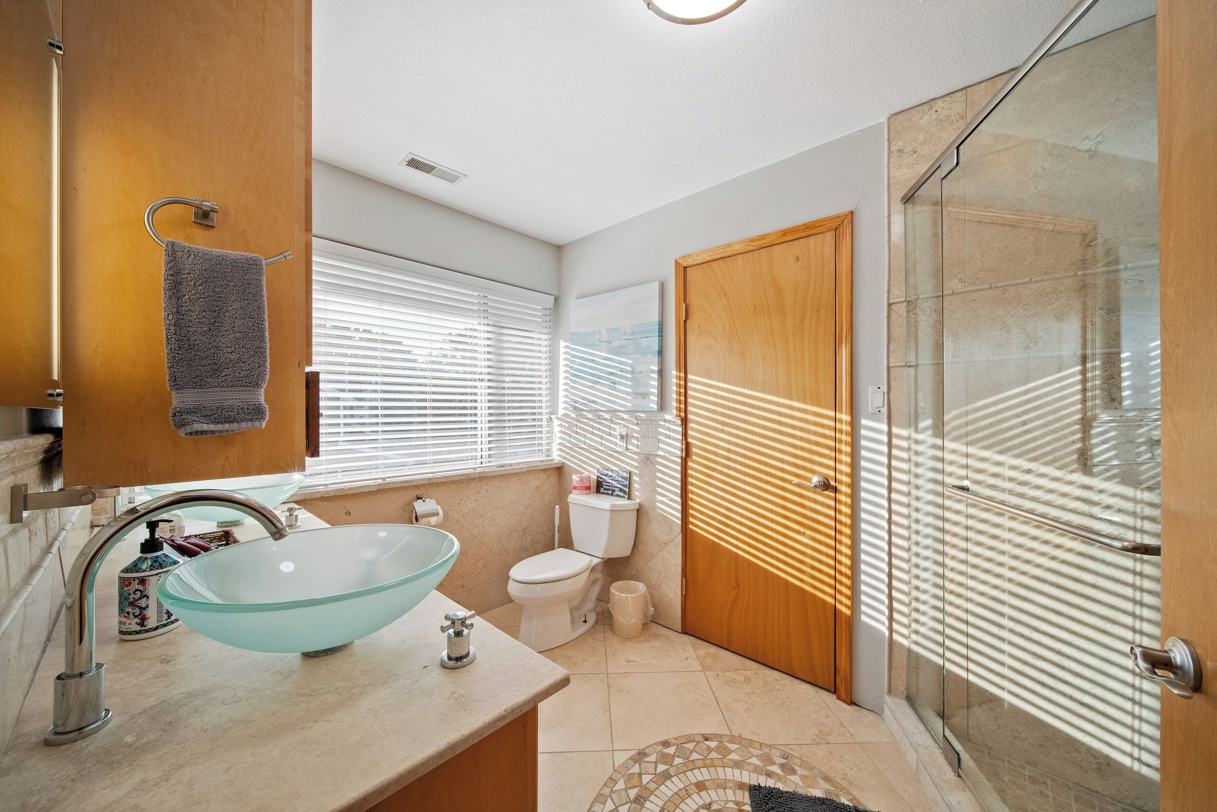 A modern bathroom with a glass bowl sink, a toilet, and a shower with a glass door.