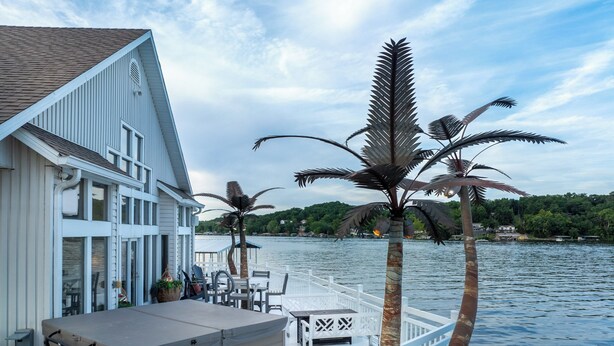 A waterfront property with a covered deck, outdoor seating, and a view of the lake.