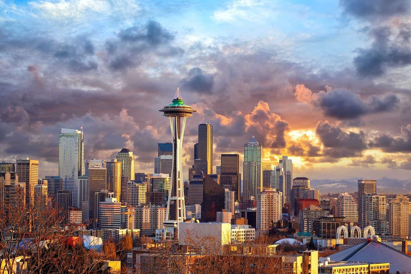 A cityscape with the Space Needle prominently in the center, surrounded by modern skyscrapers and a cloudy sky.