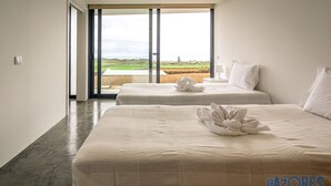 Een hotelkamer met twee bedden, uitzicht op het landschap en een groot raam.