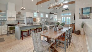 A spacious kitchen with a large island, wooden beams, and a dining area with a wooden table and chairs. - Sunset Bay 111 ST (Port Aransas)