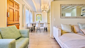 Un salón amplio con un sillón verde, un sofá color beige y una mesa de comedor con sillas.