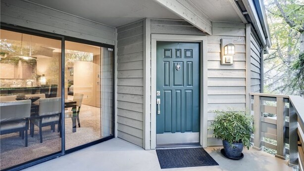 A house with a blue door, a glass sliding door entrance, a small porch, and a potted plant.