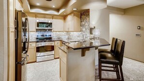 A modern kitchen with built-in appliances, a large island, and a bar stool.